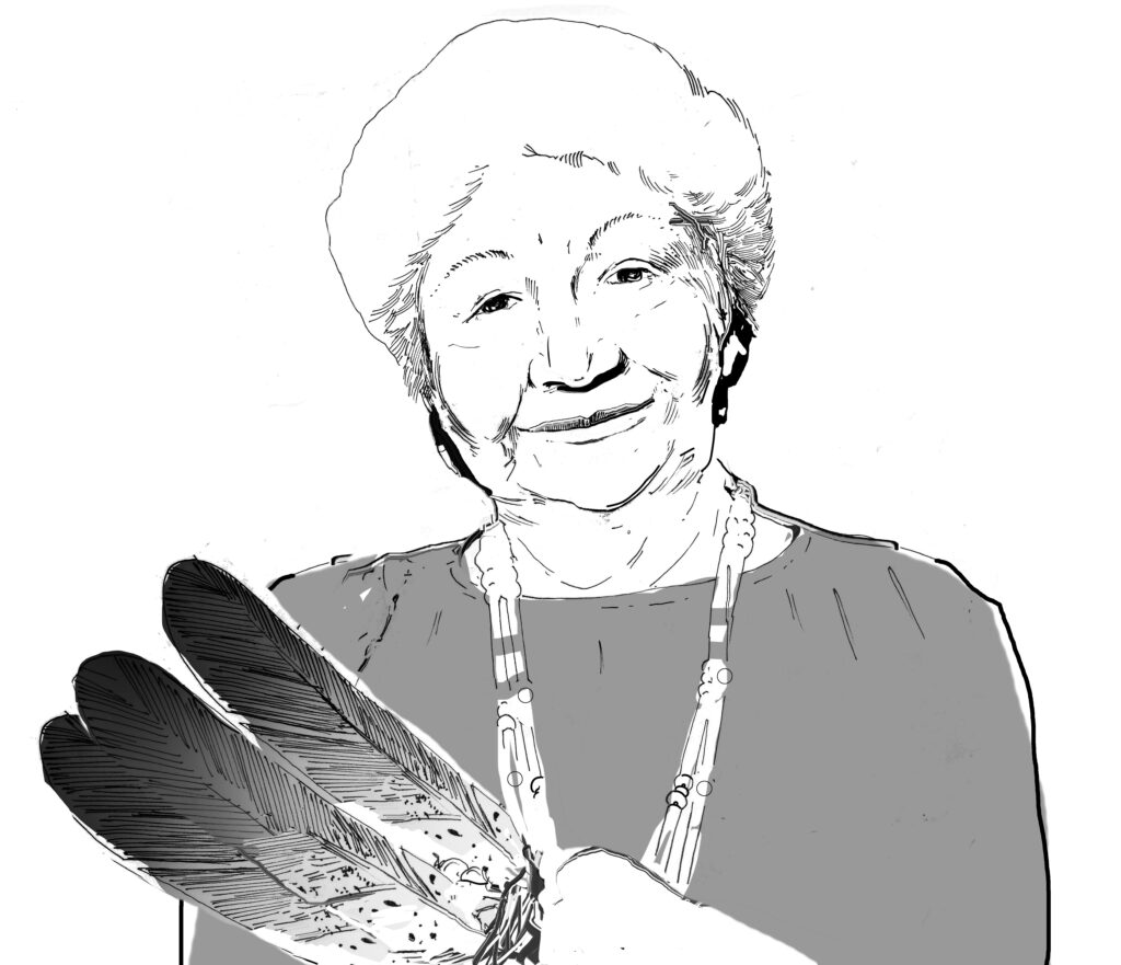 An elder woman gently smiling with an eagle feather fan. 